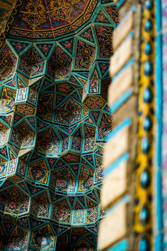 A monumental mosque facing the Atlantic Ocean, featuring a towering minaret, carved marble details, zellige tile mosaics, and a grand courtyard paved in geometric patterns