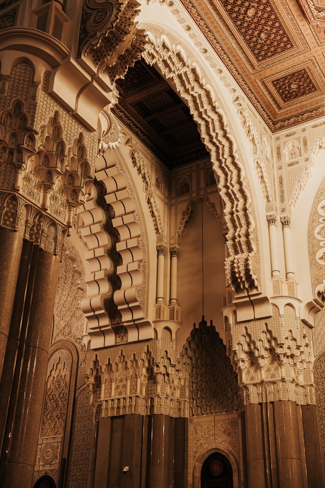 Intricate Moroccan archway with carved stucco, geometric patterns, and ornate craftsmanship inside a grand Islamic architectural interior