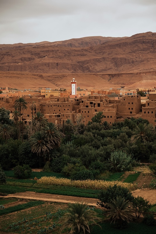 Hand‑woven Moroccan carpets folded and displayed in a stack, showing vibrant patterns, geometric motifs, and rich wool textures